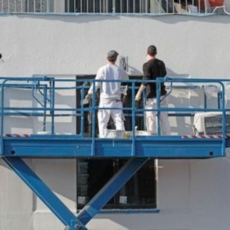 Zwei Männer arbeiten auf einem Lift an der Fassade eines Gebäudes
